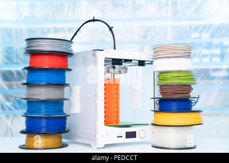ABS e PLA filament accanto alla stampante 3D. Bobine di plastica Foto Stock