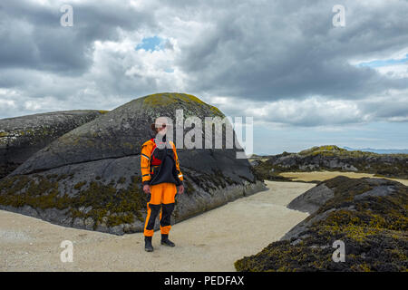 Giovane donna kayaker di mare indossando un giallo brillante drysuit. Foto Stock