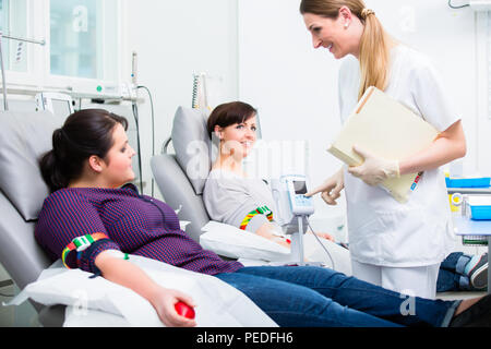 Assistente di medici la raccolta di donazioni di sangue Foto Stock