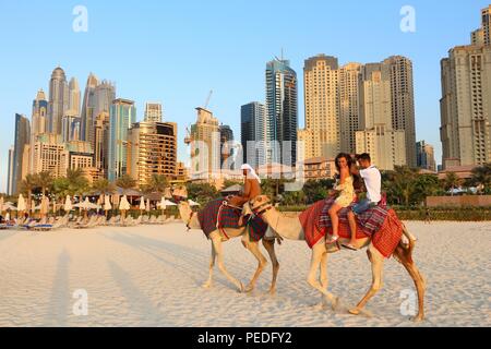 DUBAI, Emirati Arabi Uniti - 23 novembre 2017: Persone corsa cammelli nella parte anteriore del Jumeirah Beach Residence in Dubai Emirati Arabi Uniti. Dubai ha 14,9 milioni annui Foto Stock