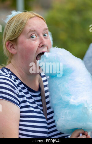 Vista ravvicinata della giovane donna prendendo un grosso morso fuori del suo cotone aka Candy Candy Floss Foto Stock