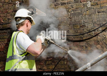 Lavoratore parete di pulizia con acqua ad alta pressione spray Foto Stock