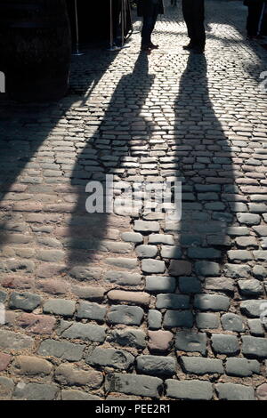 Ombre di persone aventi una conversazione su una strada di ciottoli di Camden Town, Londra Nord Foto Stock