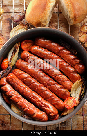 Salsicce alla griglia nella teglia da forno con aglio e cipolla Foto Stock