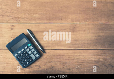 Una calcolatrice e penna su sfondo di legno con copia spazio per inserire il testo. Foto Stock