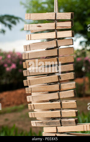 Lavanderia in legno clip abbigliamento appeso verticalmente su una stringa in country house cortile sulla vegetazione verde sullo sfondo Foto Stock