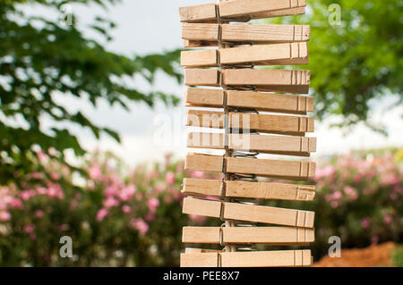 Lavanderia in legno clip abbigliamento appeso verticalmente su una stringa in country house cortile sulla vegetazione verde sullo sfondo Foto Stock