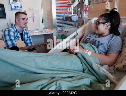 Airman 1. Classe Dylan Westmoreland, 790th Quick Response Force, riproduce musica per Samantha sorpassata un paziente in ospedale per bambini Colorado, Gennaio 6, 2016. Westmoreland ha iniziato a giocare all'età di 5 anni e a cantare intorno a 11. Egli ha rilasciato un album e cerca di creare più di altri di sentire. (U.S. Air Force foto di Airman 1. Classe Malcolm Mayfield) Foto Stock