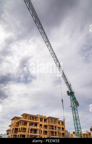 Complesso di appartamenti in costruzione con una gru accanto ad esso. Foto Stock