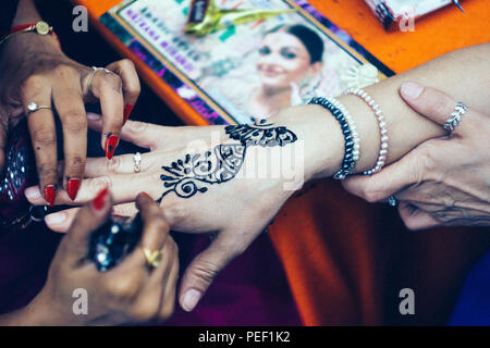 Donna artista mehendi pittura henna sulla donna mano Foto Stock