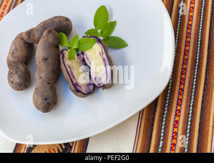 Appena sfornato patate viola su una piastra bianca. Patate di Chiloe Foto Stock