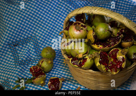 Fatte a mano cesto pieno di frutta melograno su un tessuto blu, frutta, raccolta Foto Stock