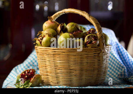 Messicane fatte a mano cesto pieno di frutta melograno su un tessuto blu, frutta, raccolta Foto Stock