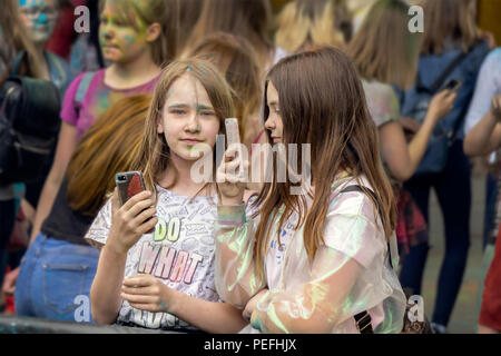 DZERZHINSK, Russia - 19 Maggio 2018: giovani ragazze con facce e capelli decorate con polvere di colore sono gli smartphone di controllo presso il festival di musica e c Foto Stock