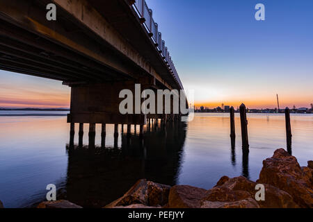 Sole che si estende su ponte e lago con riflesso in acqua Foto Stock