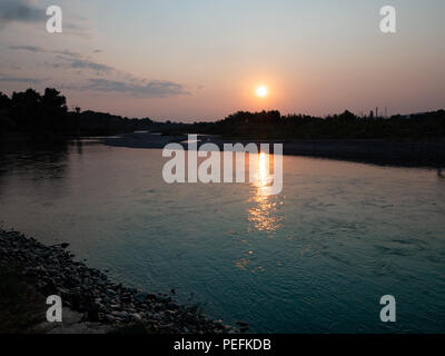 Il riflesso del sole all'alba sul fiume Yellowstone. Un banco roccioso è in primo piano. Foto Stock