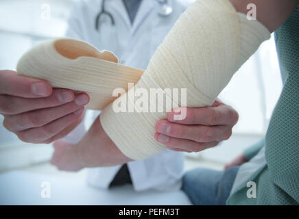 Ortopedico applicando un bendaggio sulla mano del paziente in clinica Foto Stock