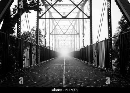 Una fitta nebbia inizia a laminazione al vecchio Fair Oaks ponte sopra il fiume americano di Fair Oaks, California. Foto Stock