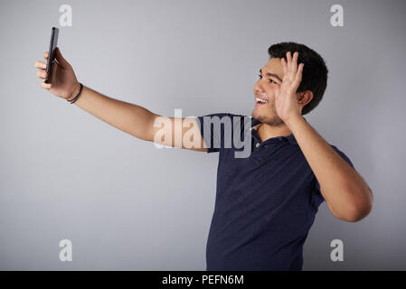 Giovani onda man mano nella chiamata videop in sfondo per studio Foto Stock