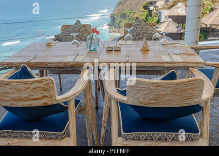 Tavolo in legno e sedie in una scogliera outdoor cafe con vista oceano, Ungasan, Bali, Indonesia. Foto Stock