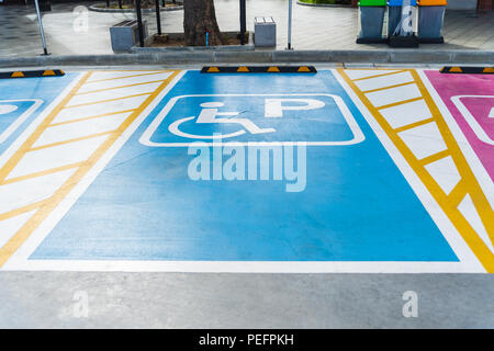 Portatori di handicap internazionale (sedia a rotelle) o parcheggio disabili simbolo dipinto in blu luminoso su parcheggio. Foto Stock