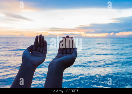 Soft focus e silhouette donna mani pregando per la benedizione di Dio durante il tramonto sullo sfondo. Il concetto di speranza. Foto Stock