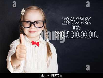 Bambino felice ragazza in bicchieri con il pollice in alto è di andare a scuola per la prima volta. Si torna a scuola concept Foto Stock