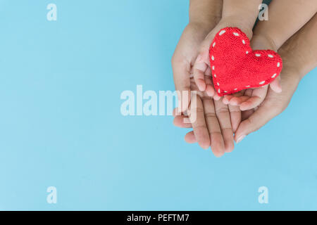 Vista dall'alto di adulto e bambino azienda cuore rosso in mani, Felice le relazioni familiari, San Valentino, Festa della Mamma, di amore e di cura di salute concetto. Foto Stock