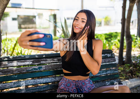 Hipster ragazza ottenendo un selfie su una panca in legno Foto Stock