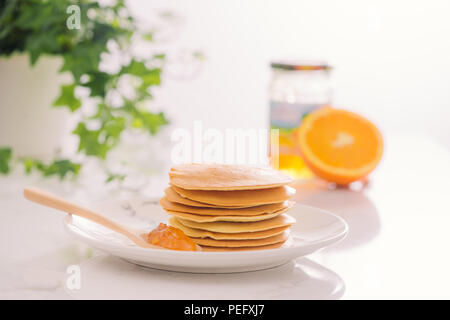 Pila di deliziose frittelle sulla piastra isolata su bianco Foto Stock