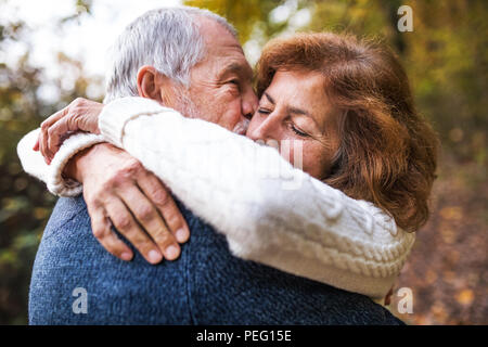 Un close-up di una coppia senior abbracciando in un autunno natura, baciare. Foto Stock