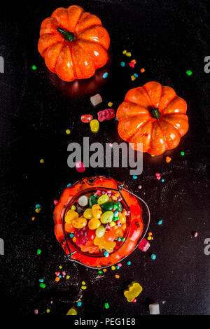 I dolci di Halloween con sfondo colorato di caramelle, sfondo nero in vista dall'alto uno spazio di copia Foto Stock