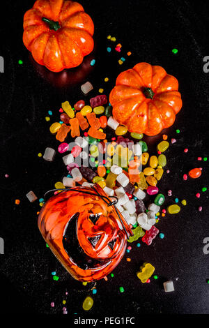 I dolci di Halloween con sfondo colorato di caramelle, sfondo nero in vista dall'alto uno spazio di copia Foto Stock