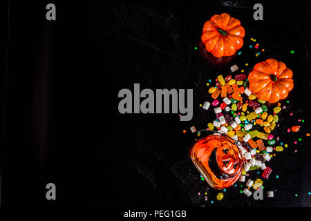 I dolci di Halloween con sfondo colorato di caramelle, sfondo nero in vista dall'alto uno spazio di copia Foto Stock