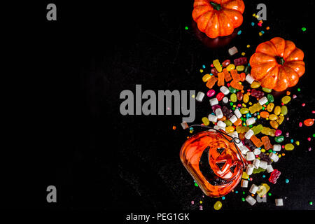 I dolci di Halloween con sfondo colorato di caramelle, sfondo nero in vista dall'alto uno spazio di copia Foto Stock