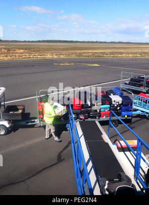 Handler aeroportuale bagaglio di carico essendo posto su un nastro trasportatore in un piano a Beziers Cap d Agde aeroporto, Francia Foto Stock