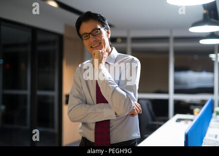 Happy Businessman matura sorridente in ufficio di notte Foto Stock