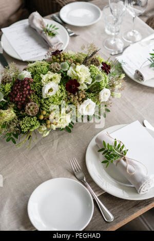 Ordinatamente intrecciati in un tubo sala da pranzo igienico decorate con un rametto di pistacchio. Banchetti per matrimoni o cene di gala. Il tavolo e sedie per gli ospiti, Servita con posateria e stoviglie. party sulla terrazza Foto Stock