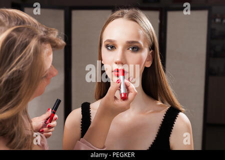 Trucco donna applicando un rossetto rosso su un modello Foto Stock