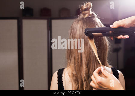 Parrucchiere curling una ciocca di capelli di un modello Foto Stock