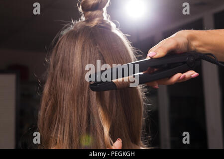Parrucchiere curling una ciocca di capelli di una ragazza Foto Stock