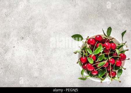 Le ciliege fresche sulla piastra, vista dall'alto. Rosso, di ciliege acide con foglie. Foto Stock