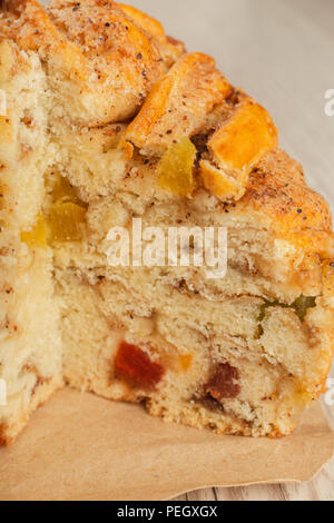 Torta con frutta candita in un taglio su un sfondo di legno. Foto Stock
