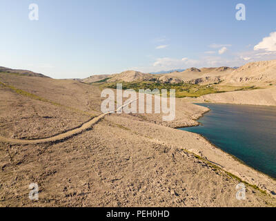 Vista aerea di una tortuosa strada che corre lungo le coste croate, sterrato, isola di Pag vicino Rucica beach a Metajna. Selvaggio e incontaminato Foto Stock