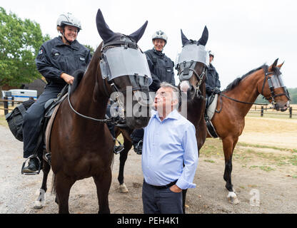 Willich, Germania. Il 15 agosto, 2018. Herbert Reul (CDU), il ministro degli Interni dello stato della Renania settentrionale-Vestfalia, è in piedi di fronte a poliziotti montati durante una visita per il NRW squadra di equitazione. Il ministro è informato circa il lavoro, operazioni e addestramento di piloti di polizia. Credito: Christophe Gateau/dpa/Alamy Live News Foto Stock