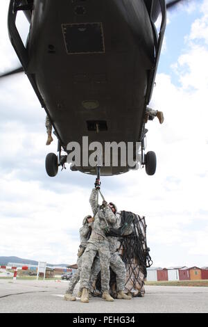 Soldati attualmente assegnati alle multinazionali del Battle Group-East tentativo di collegare un pallet caricato a un UH-60 Black Hawk elicottero hovering overhead durante il carico di imbracatura di formazione, 19 Agosto, 2015, a Camp Bondsteel in Kosovo. La formazione è stata condotta per aiutare a familiarizzare i soldati, che funge da parte di della NATO a sostegno della pace missione in Kosovo, con imbracatura in elicottero le operazioni di carico e le procedure. (U.S. Foto dell'esercito da Lt. Col. Gilbert Buentello, multinazionale battaglia Group-East) Foto Stock