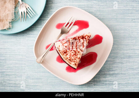 Torta rossa del velluto fetta su sfondo blu. Vista superiore Foto Stock