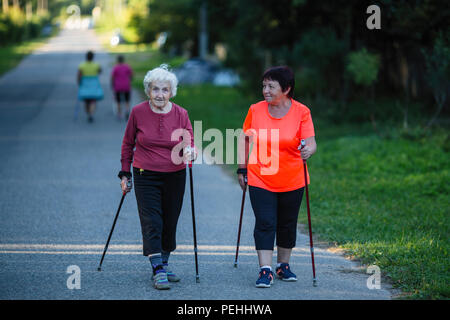Una donna anziana è impegnato nel Nordic walking con sua figlia adulta. Foto Stock