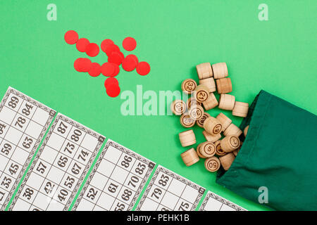 Lotto in legno Barili con borsa di stoffa, gioco di carte e chip rossi su sfondo verde. Gioco di bordo del lotto. Vista da sopra con lo spazio di copia Foto Stock