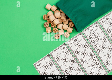 Lotto in legno Barili con borsa di stoffa e carte da gioco su sfondo verde. Gioco di bordo del lotto. Vista da sopra con lo spazio di copia Foto Stock